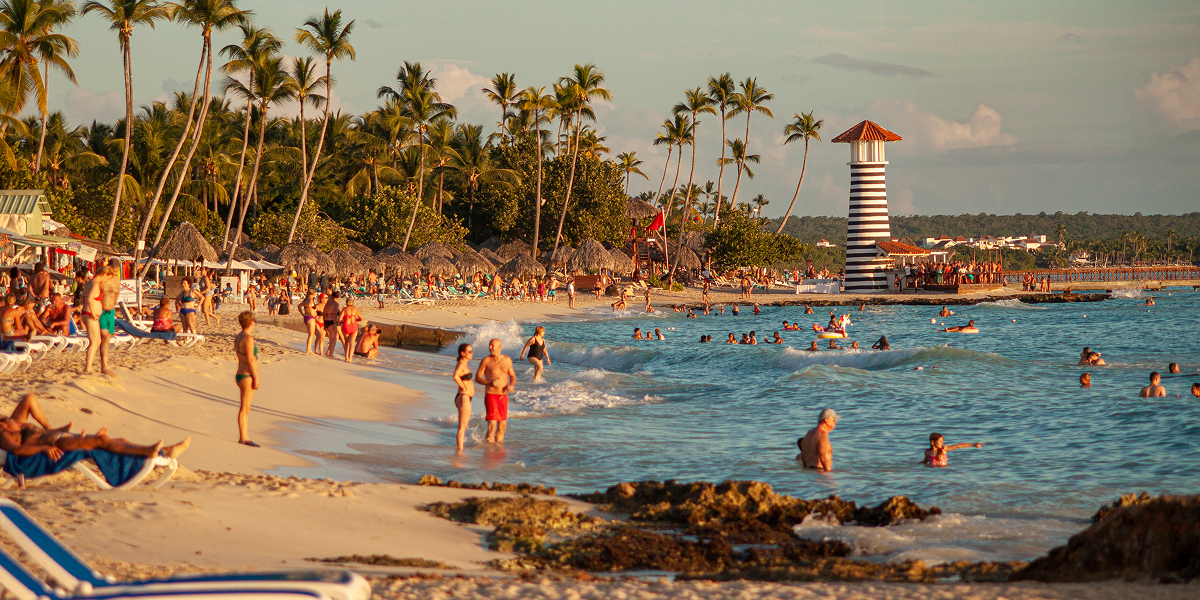 Panoramic view of Anjuna Beach with colorful shacks, golden sand, and turquoise waters during golden hour